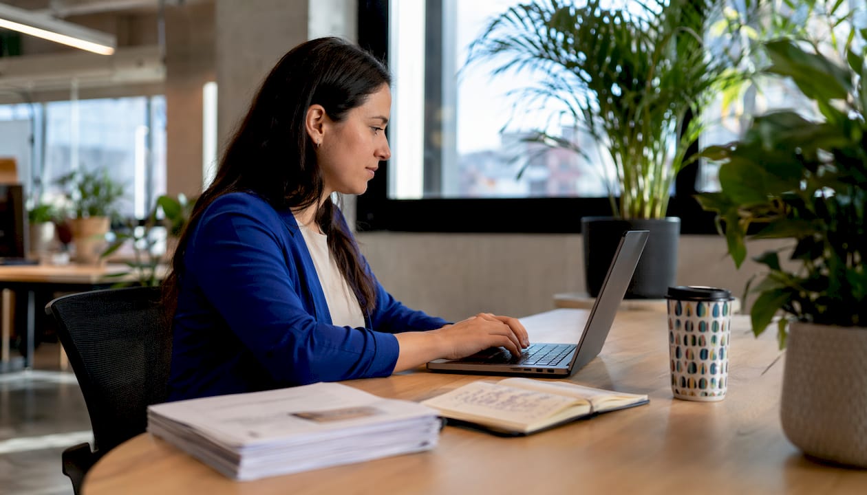 Side view of woman reviewing remote staffing profiles on laptop